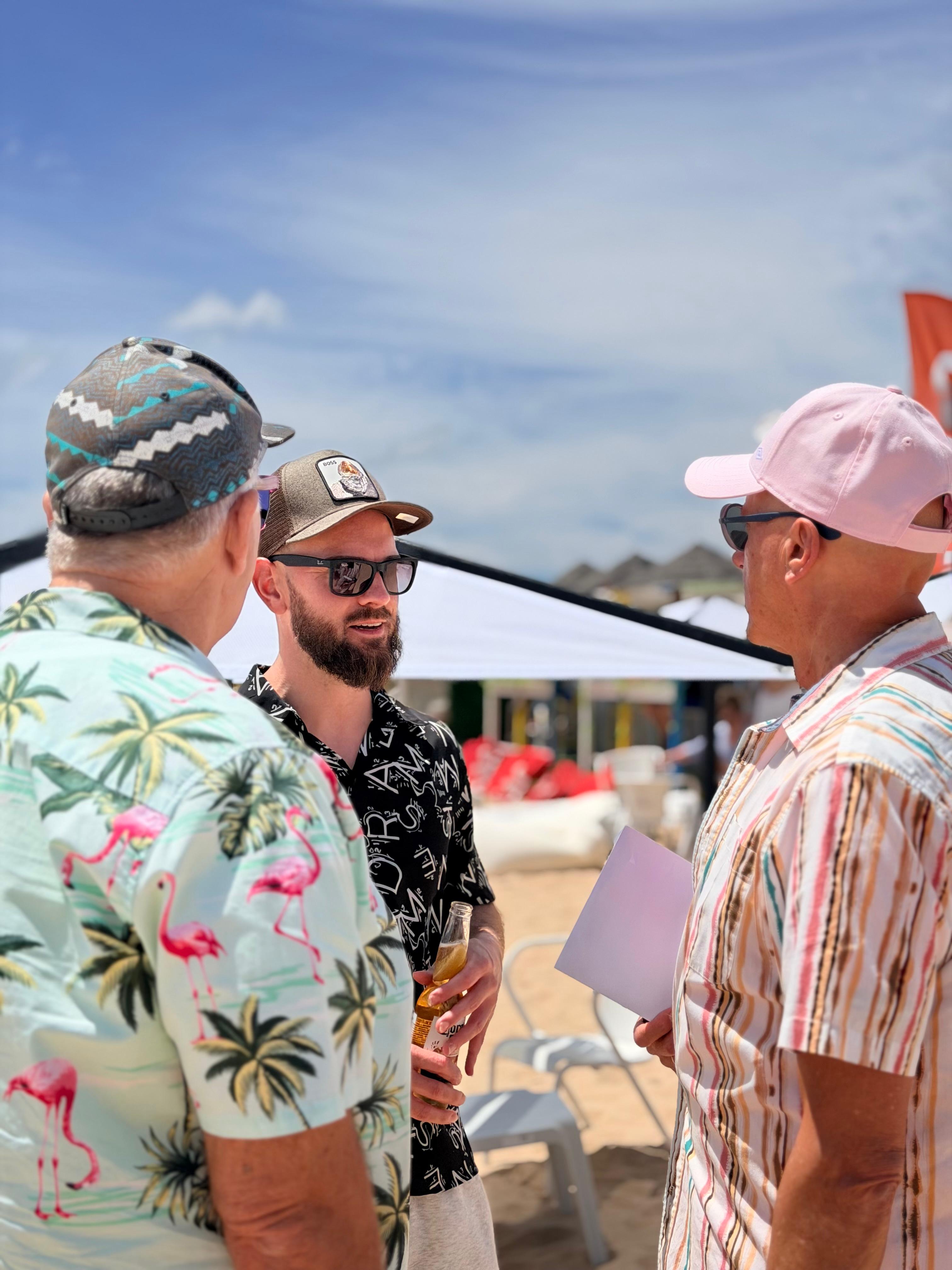 Three guests in floral shirts chatting at the Pirata Beach Bash on Meia Praia.