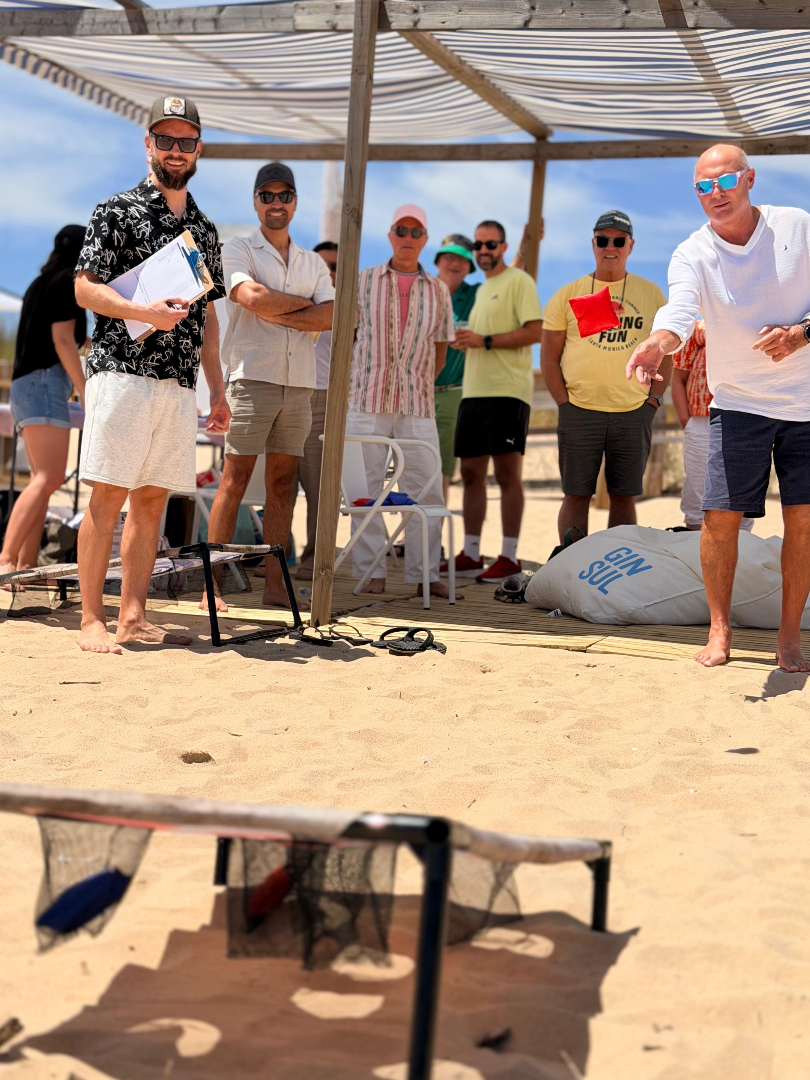 A guest mid-throw at the cornhole board, with spectators watching.