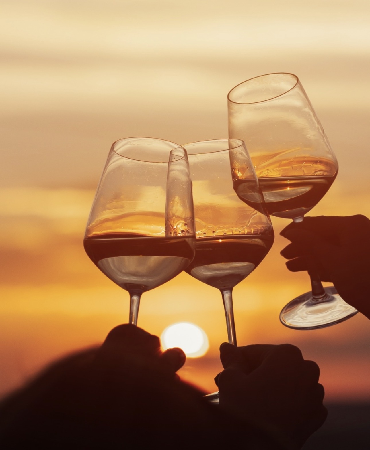 Three wine glasses clinking against the Algarve sunset.
