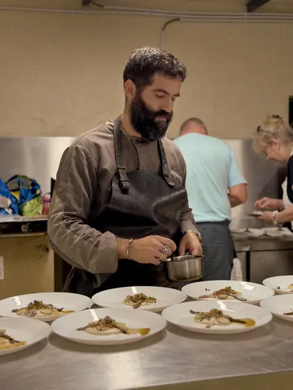 Chef João Marreiros finishing plates at the kitchen pass during Vine and Fire.